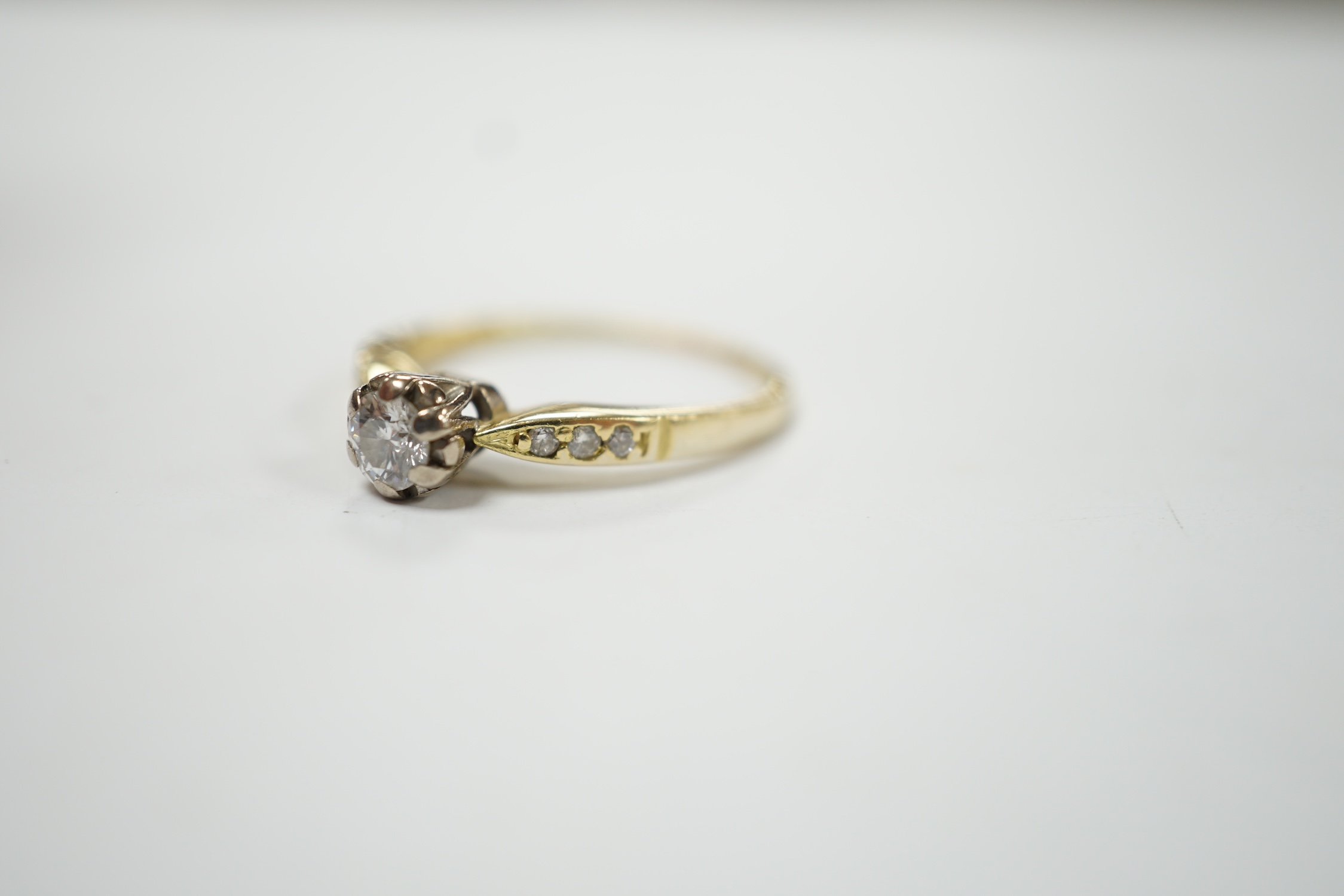 A modern 18ct gold and illusion set single stone diamond ring, with six stone diamond chip set shoulders, size O, gross weight 3 grams. Good condition.